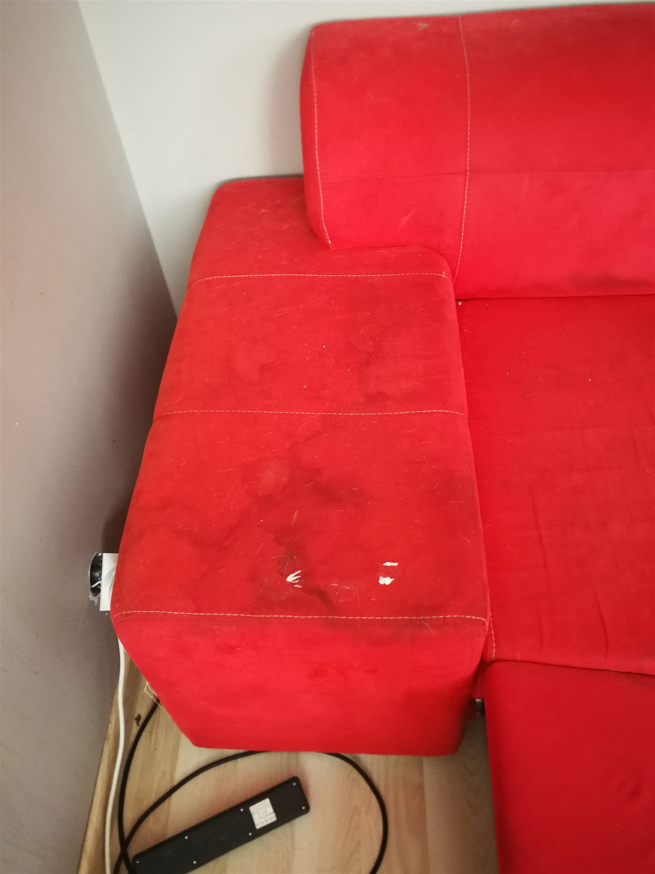 Podłokietnik czerwonej kanapy przed czyszczeniem